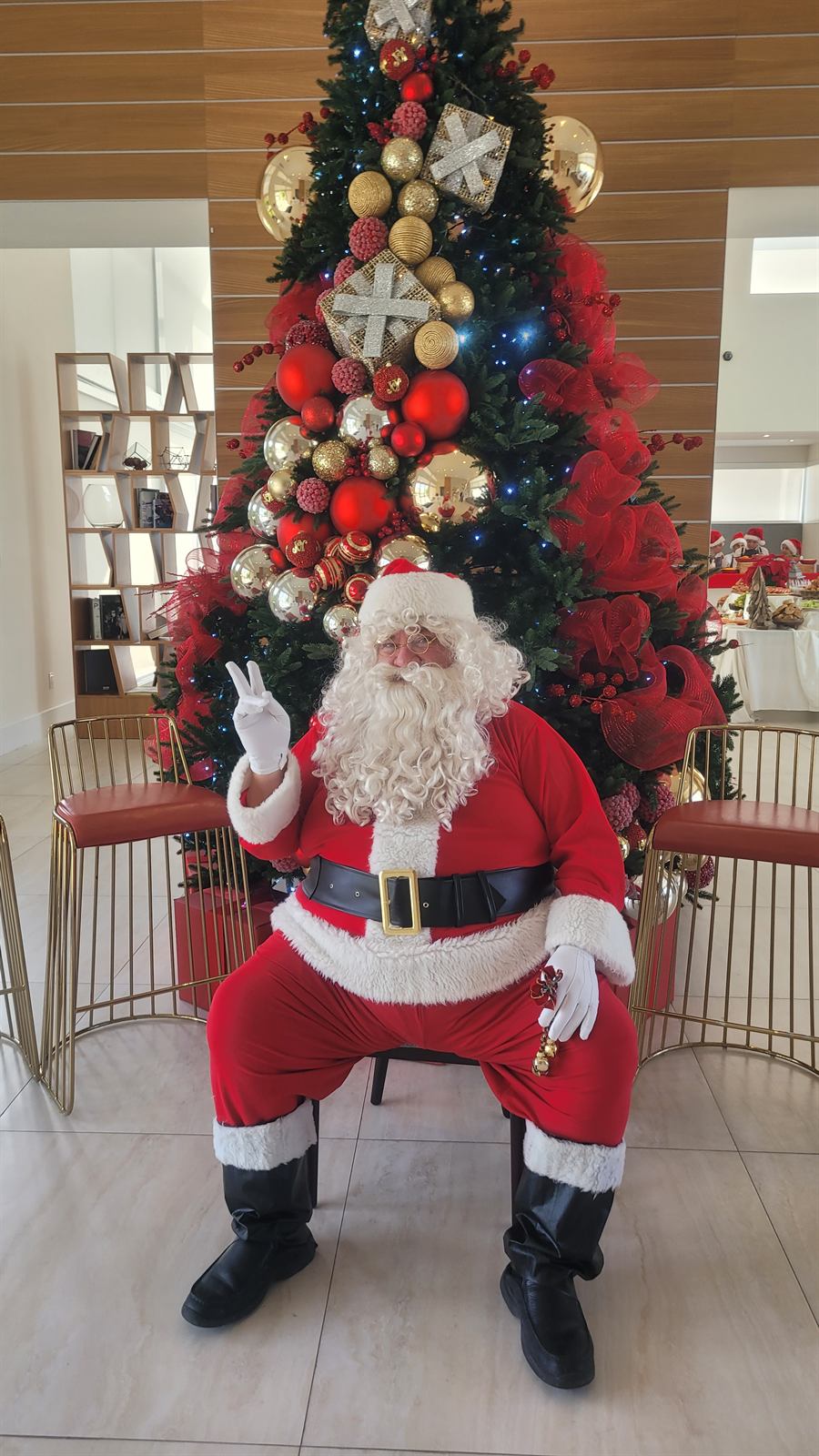 Papa Noel seated by a decorated Christmas tree