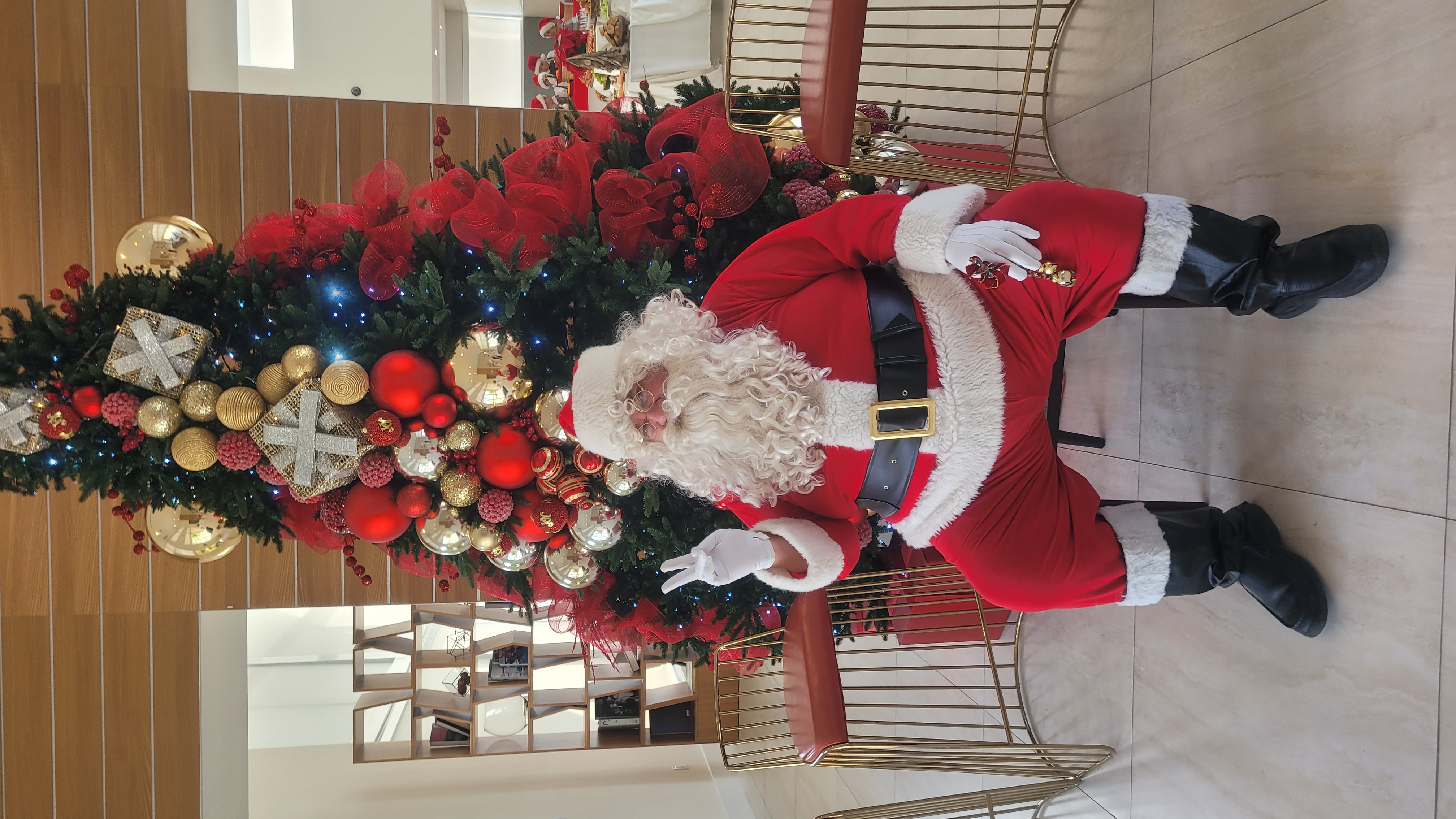 Papa Noel seated beside a decorated Christmas tree